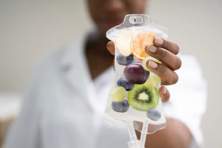 A person holds an IV bag filled with a variety of fruits.