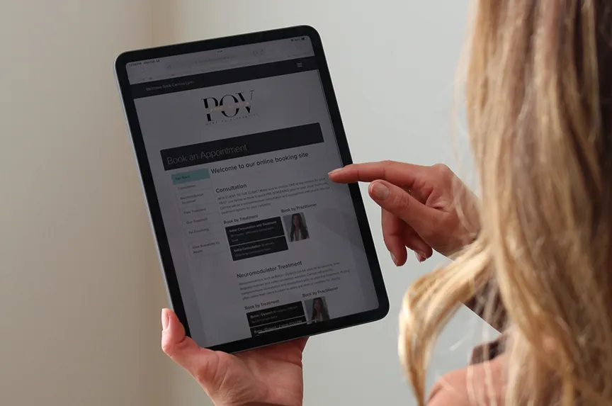 A person holds a tablet, browsing an online booking site for consultations and microneedling treatments.