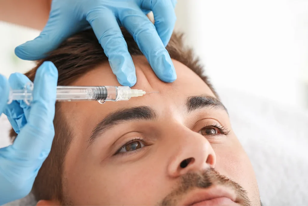 Person receiving an injection in the forehead from a gloved hand.