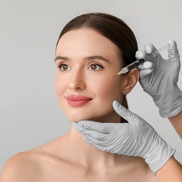 A woman receives a Sculptra injection in her cheek from a gloved medical professional.