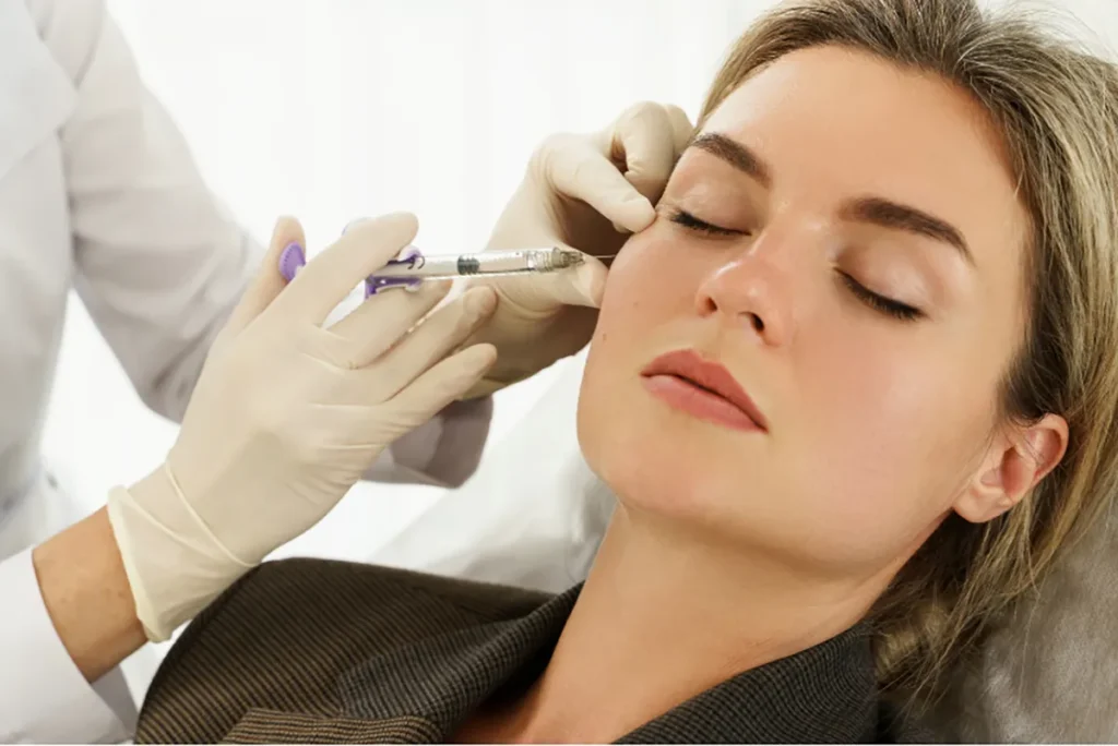 Person receiving a filler injection from a medical professional wearing gloves.